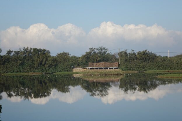 Wooden structure on an island surrounded by trees and water.